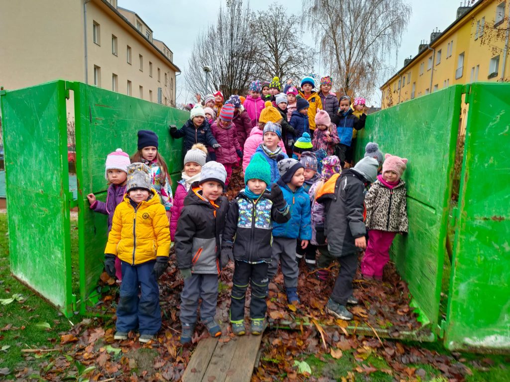 Děti stojí v kontejneru na listí.