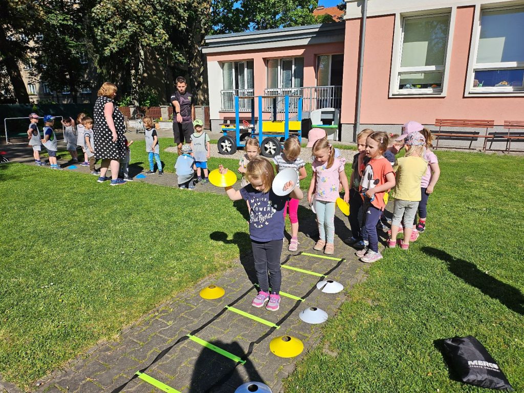 Děti cvičí na zahradě MŠ.
